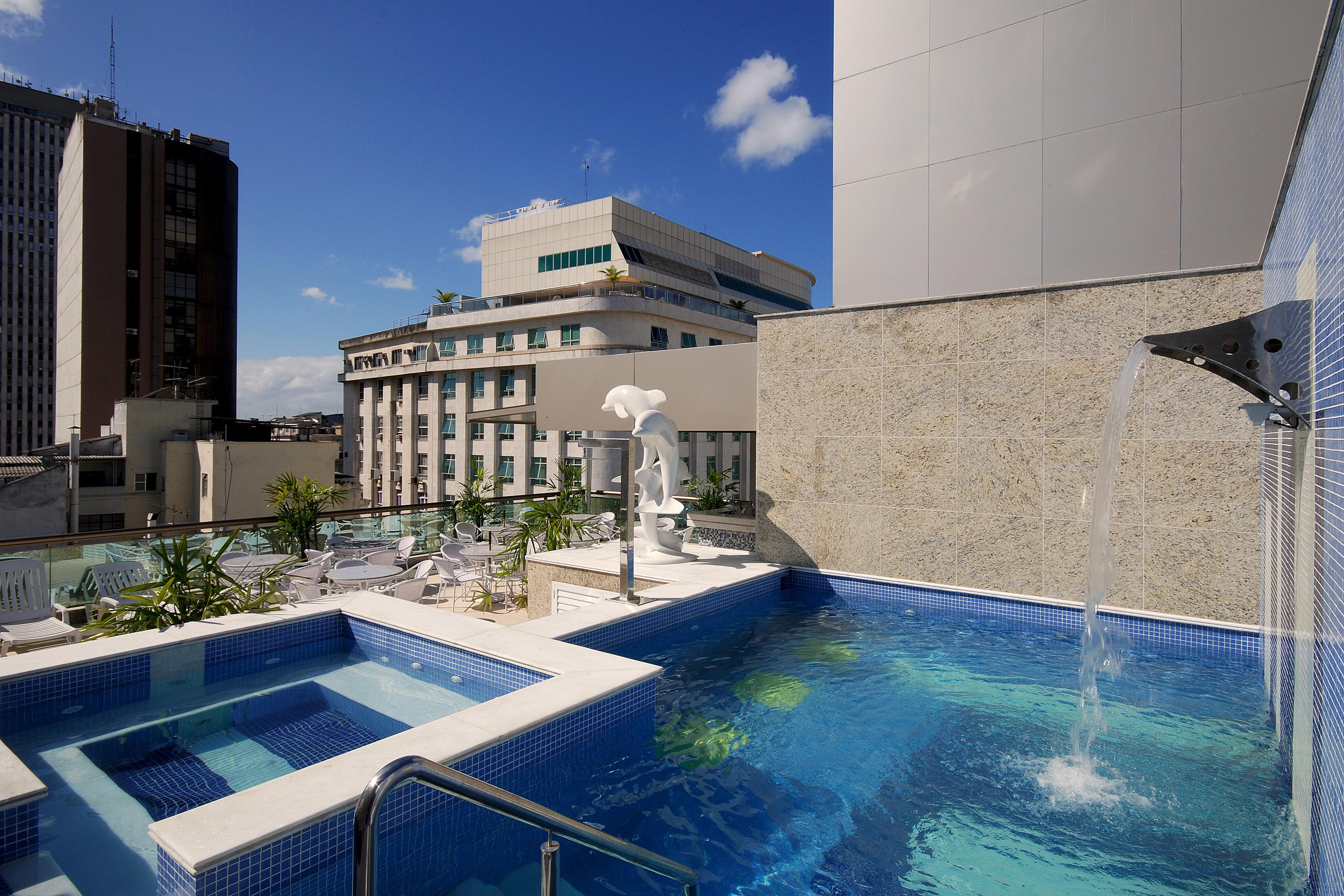 Hotel Atlantico Business Centro Rio de Janeiro Exterior foto The photo shows a rooftop area featuring a swimming pool and a spa. The pool is inviting with a clear blue water, and there appears to be a waterfall feature. Surrounding the pool are areas for relaxation, possibly with sun loungers. In the backgroun